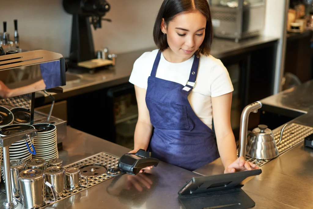 smiling-asian-girl-barista-working-cafe-counter-processing-orders-using-pos-terminal-receiving